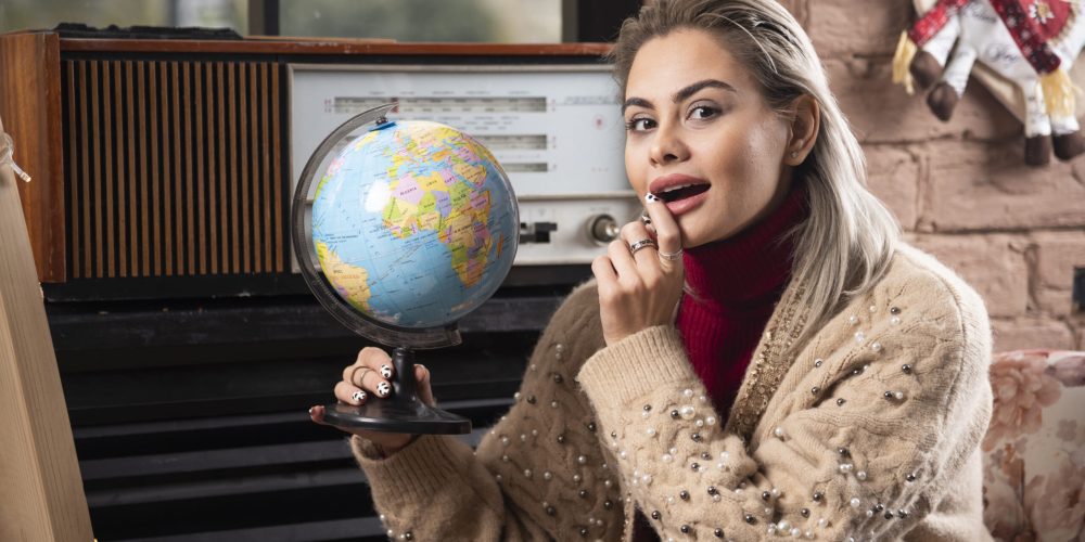 Portrait of beautiful lady holding a world globe . High quality photo